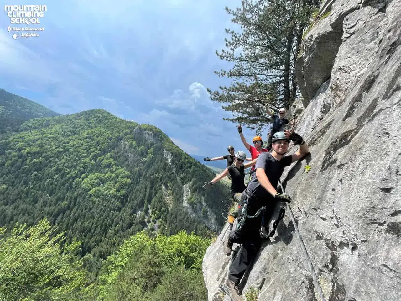 Grupa ludzi na via ferrata, ucząca się jak pokonywać trudności skalne. To świetny sposób na poznanie, co to ferrata i jak się na niej czuć.