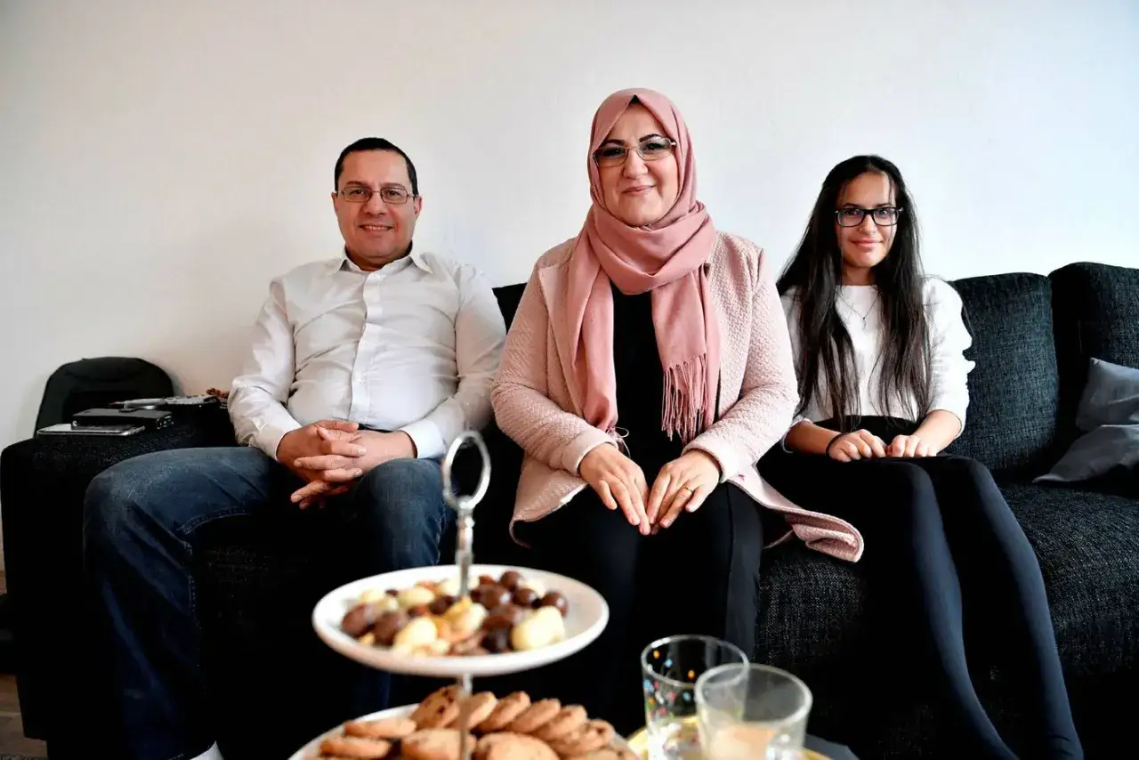 Familj samlad f&ouml;r en mysig muslimsk jul. De sitter p&aring; en soffa med en bricka med godsaker framf&ouml;r sig.