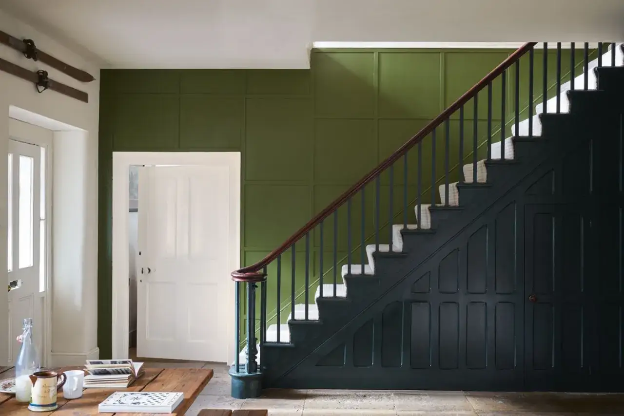 Entr&eacute;e avec escalier : le vert for&ecirc;t mural contraste avec le bleu nuit du mobilier sous l'escalier. Quelle couleur pour une entr&eacute;e avec escalier ?