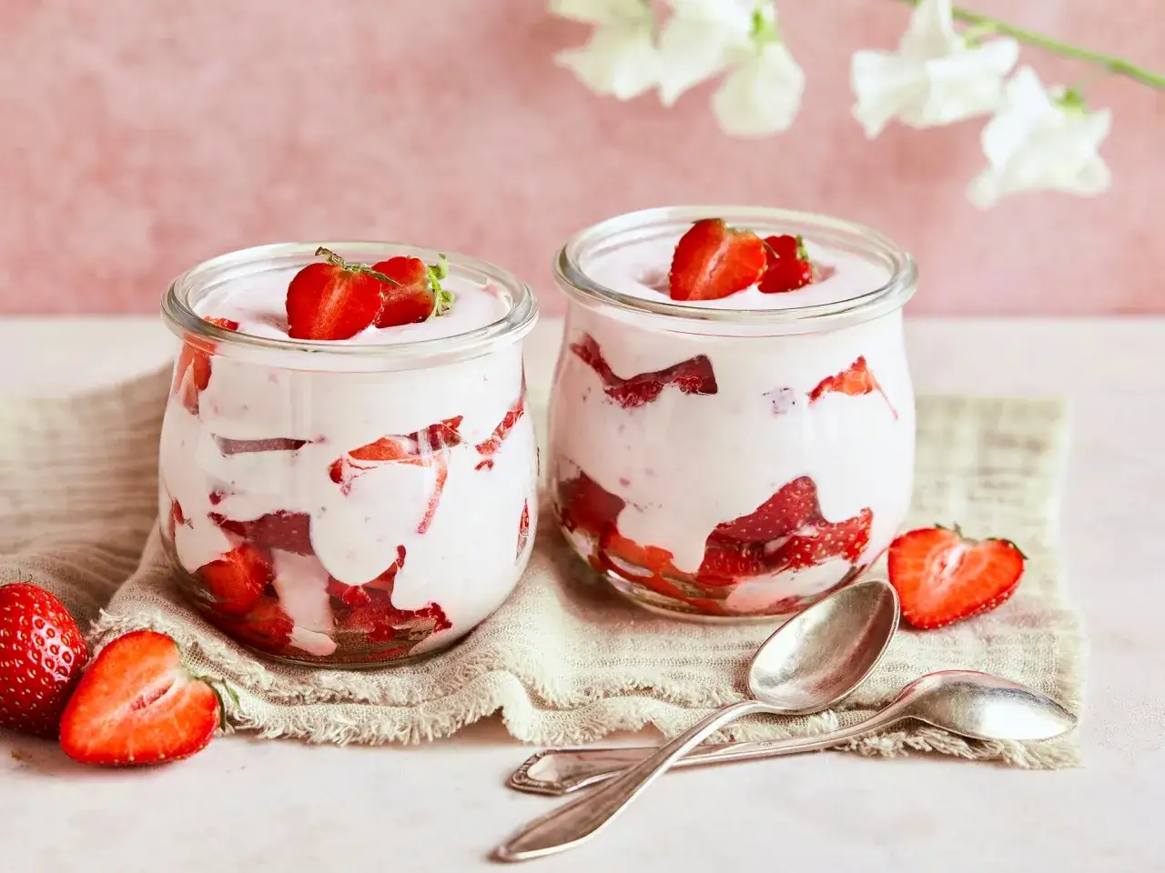 Zwei Gl&auml;ser mit cremigem Erdbeer Quark Dessert, garniert mit frischen Erdbeeren. Ein leichter Genuss f&uuml;r warme Tage.