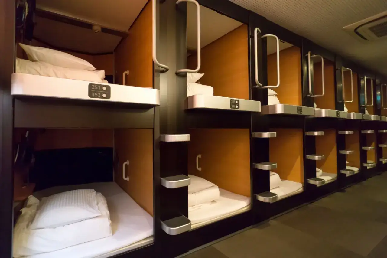 Rzędy kompaktowych kapsuł hotelowych, gdzie każdy pok&oacute;j to **najmniejszy hotel na świecie**. Widać ł&oacute;żka z pościelą i poduszkami.
