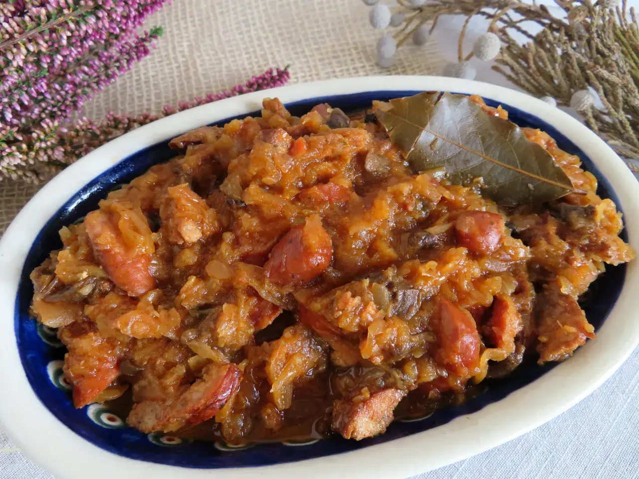 Pyszny bigos z kiszonej kapusty z kiełbasą i grzybami, podany w tradycyjnej misie.
