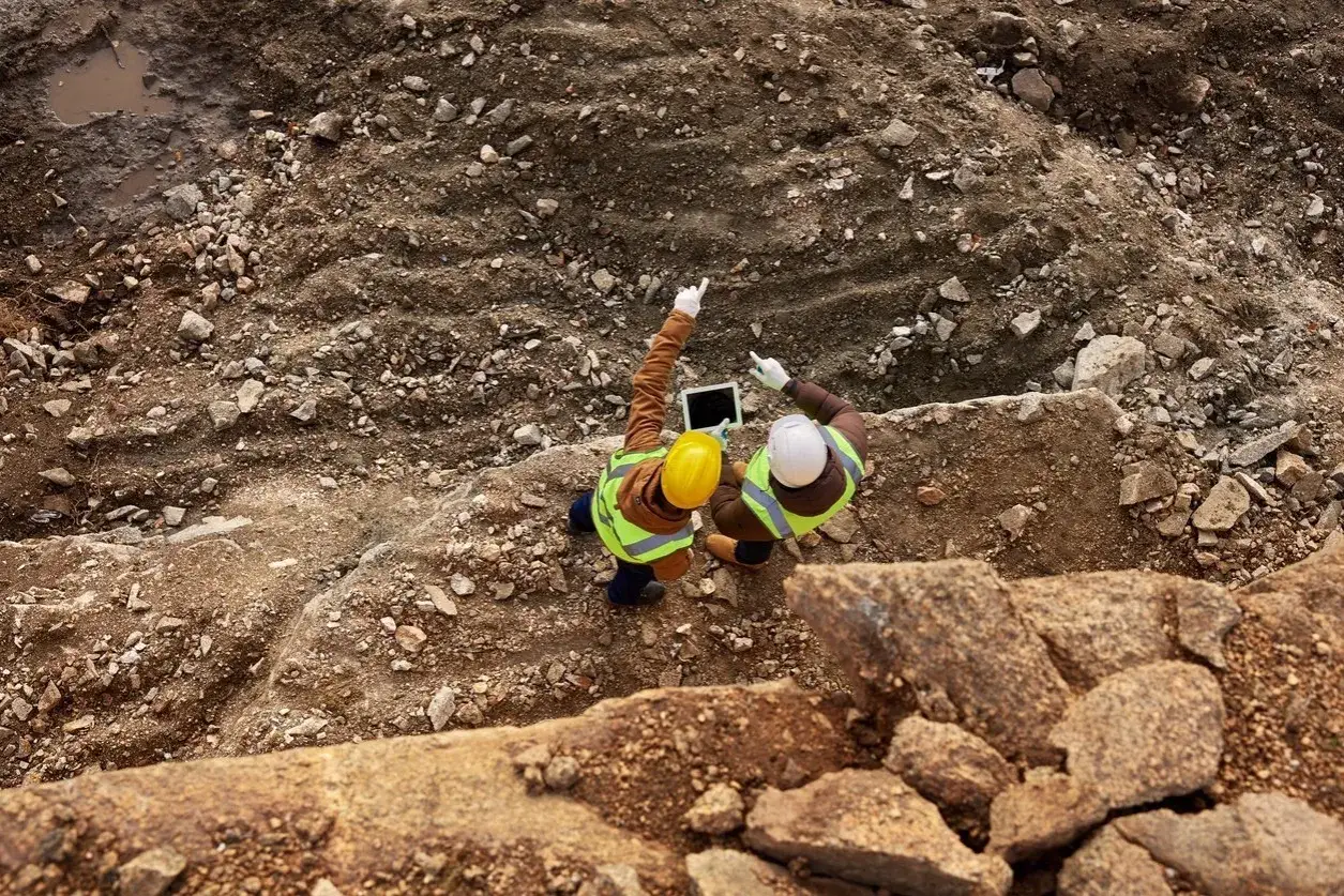 Dos ingenieros revisan planos en una tablet en una obra. El control de calidad en construcción es esencial para el éxito del proyecto.