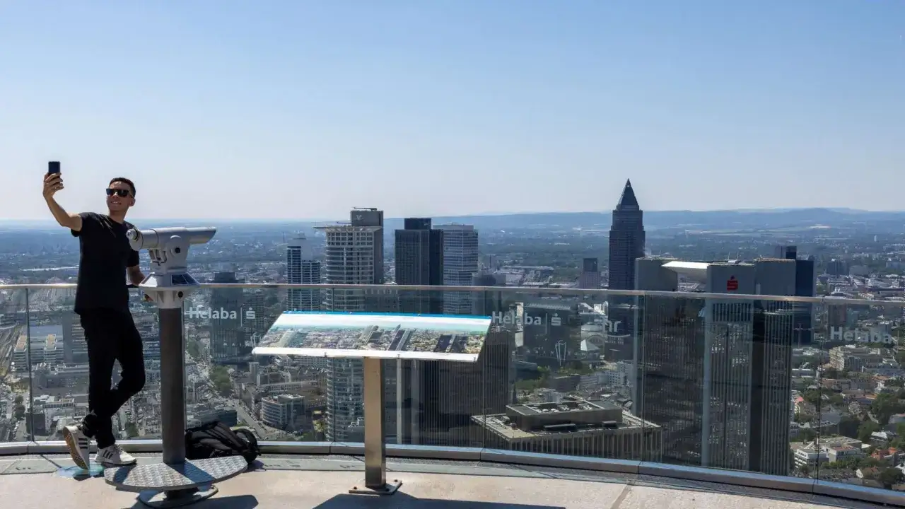 Mann macht Selfie mit Fernrohr vor Skyline Frankfurts. Perfekter Tag f&uuml;r Sightseeing Frankfurt.
