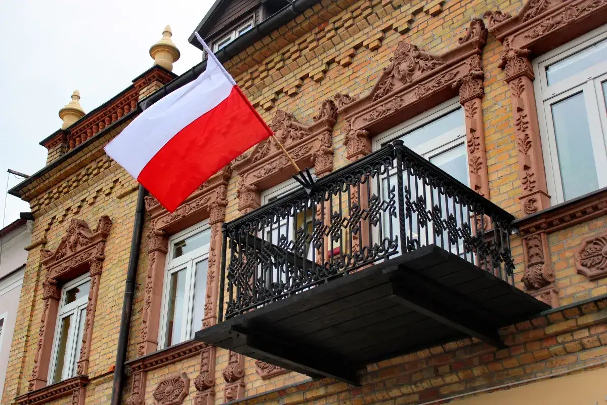 Biało-czerwona flaga powiewa na zabytkowej kamienicy. Kiedy zdjąć flagę po 3 maja? Zazwyczaj do zachodu słońca.