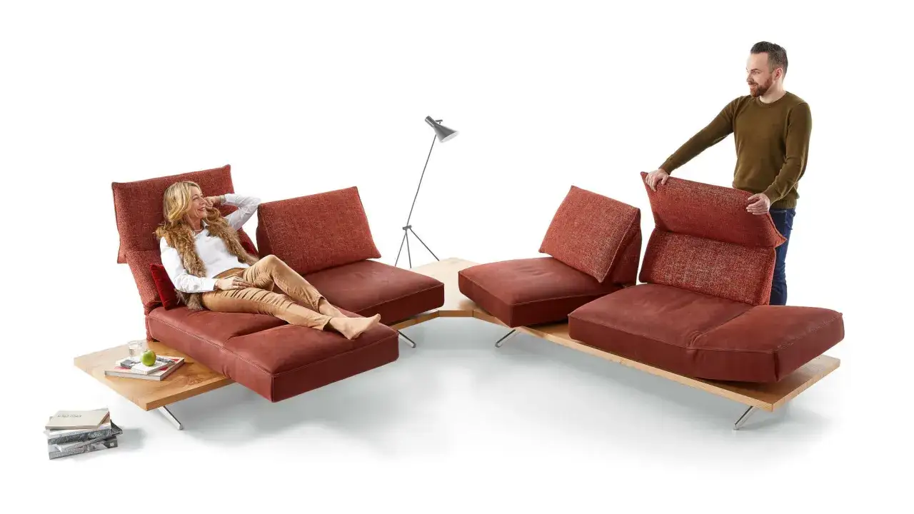 Moderne sofa arten: Frau entspannt auf rotem Ecksofa, Mann passt Rückenkissen an.