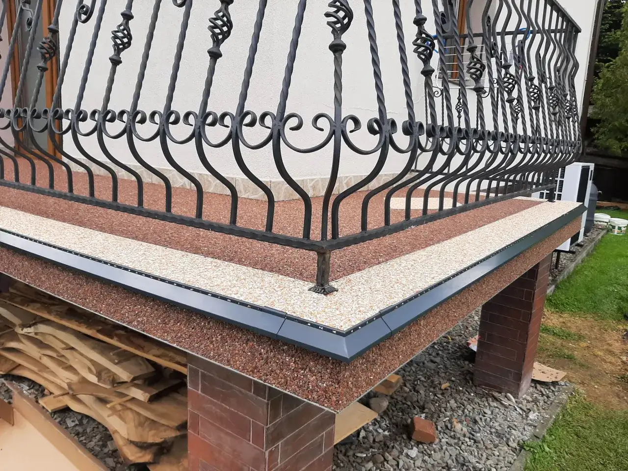 Nowy kamienny dywan koszt 1m2 to eleganckie wykończenie tarasu. Widać ozdobną balustradę i materiały budowlane.
