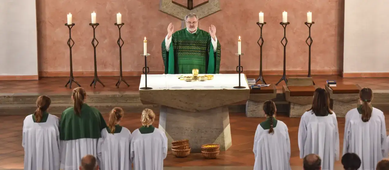 Priester feiert Messe, Kinder in Alben und Chorhemden. Was bedeutet Gloria? Ein Moment der Anbetung und des Friedens.