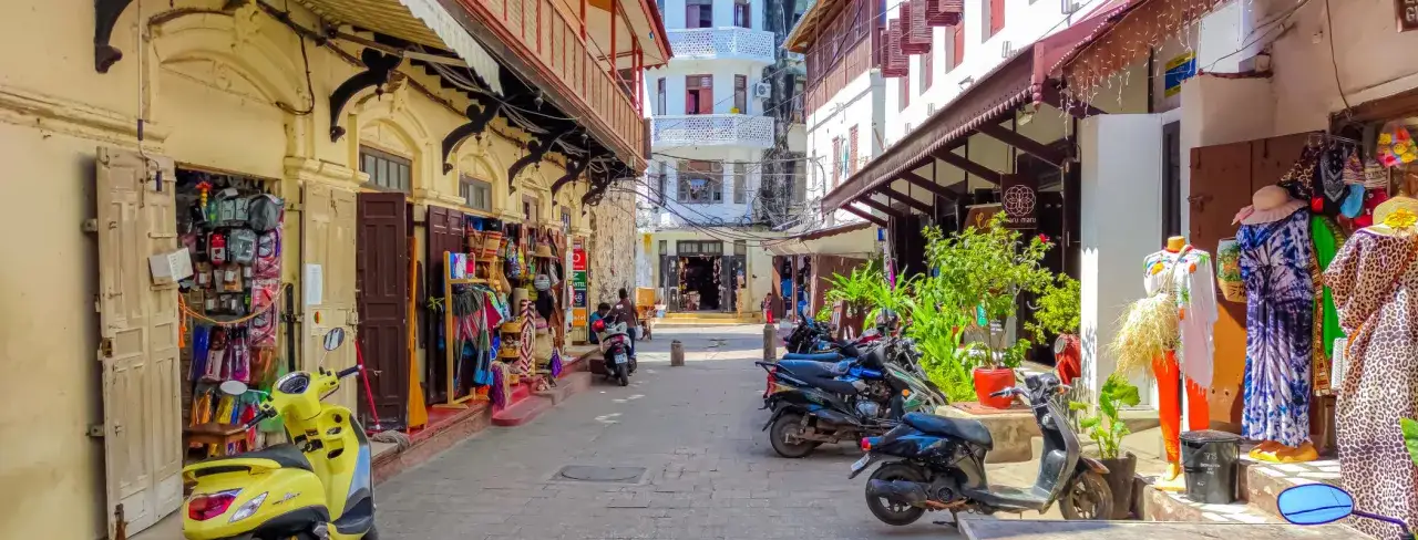 Zanzibar co zobaczyć: wąskie uliczki kamiennego miasta, kolorowe stragany z pamiątkami, skutery i tradycyjna architektura.