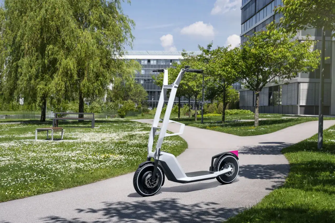 Trottinette électrique blanche au design futuriste, évoquant l'innovation d'une bmw trottinette, sur un chemin de parc verdoyant.