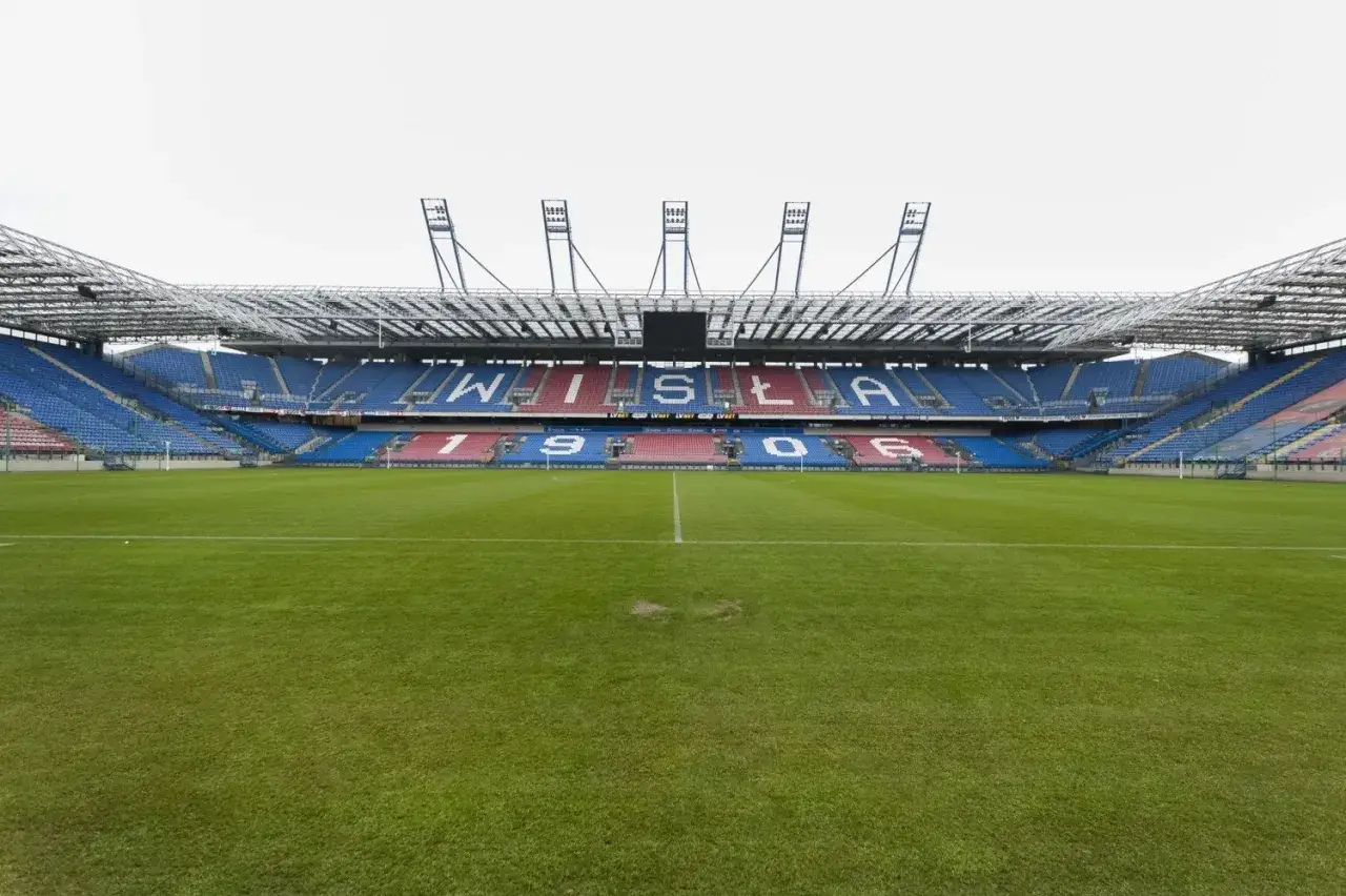 Stadion z trybunami w barwach Wisły Kraków. Na górnym poziomie napis 