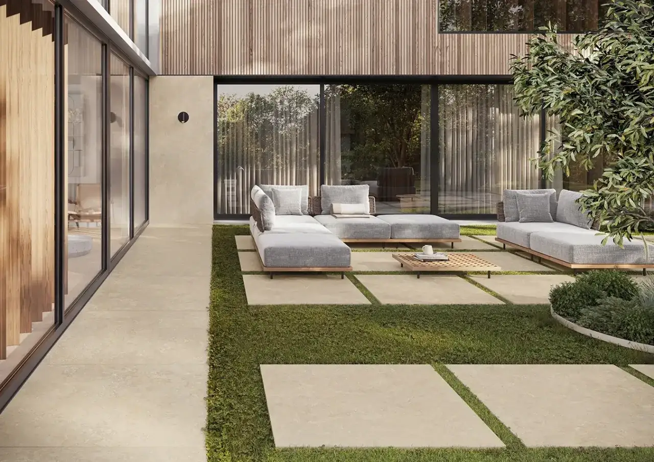 Un elegante patio moderno con divani grigi e pavimentazione in travertino, che mostra cos'è il travertino: una pietra naturale resistente e bella.