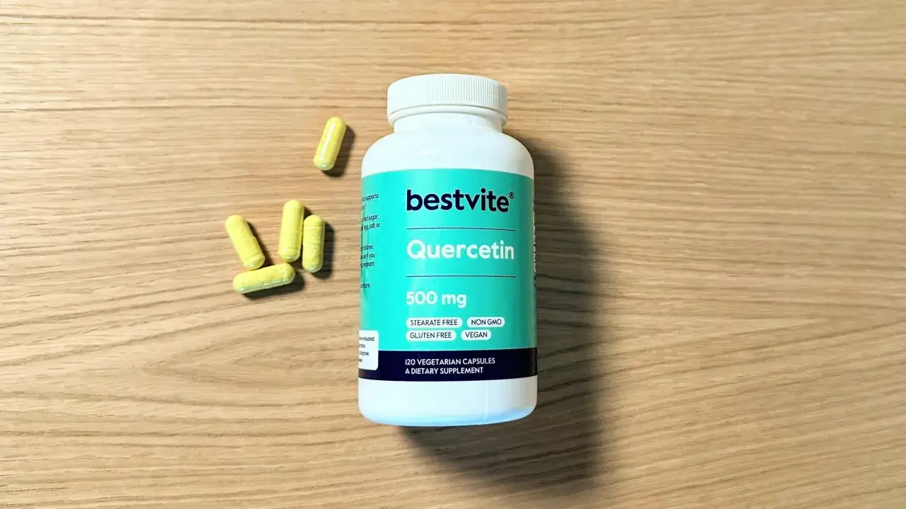Flacone di Quercetina 500 mg e capsule gialle su legno. Informazioni sulle possibili quercetina controindicazioni sono stampate sull'etichetta.