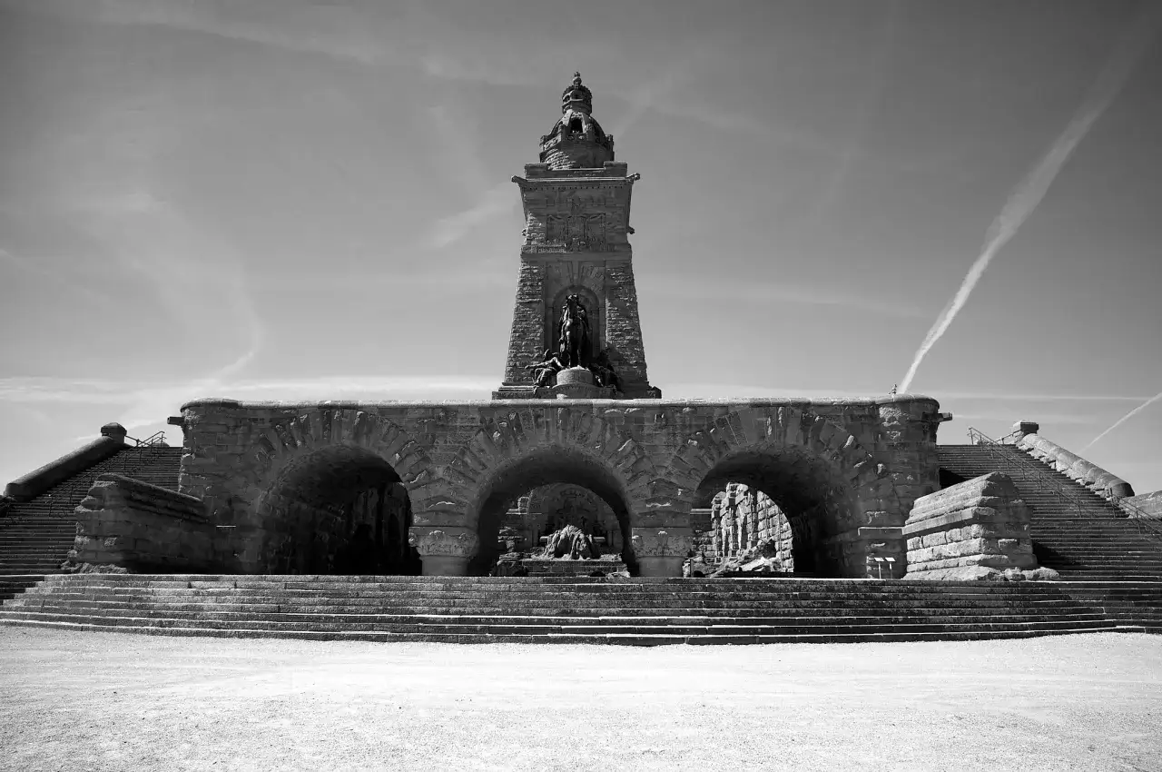 Monumentalna budowla z kamienia z łukami i schodami, przypominająca o czasach Barbarossy.