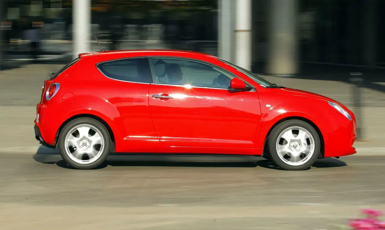 Czerwone Alfa Romeo Mito w ruchu, idealne dla tych, którzy szukają sportowych wrażeń i pozytywnych alfa romeo mito opinie.