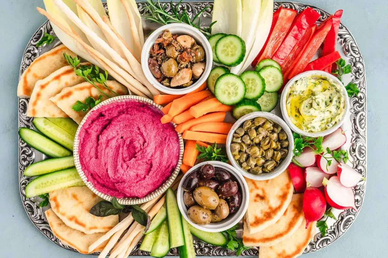 Bunte Mezze-Platte mit Hummus, Oliven, Kapern, Gem&uuml;se-Sticks und Pitabrot &ndash; perfekt f&uuml;r gesellige Runden und k&ouml;stliche Mezze Rezepte.