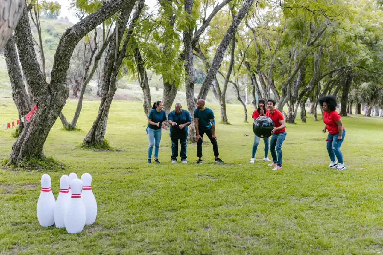 Une équipe s'amuse lors d'une sortie team building dans un parc, jouant au bowling géant en plein air.