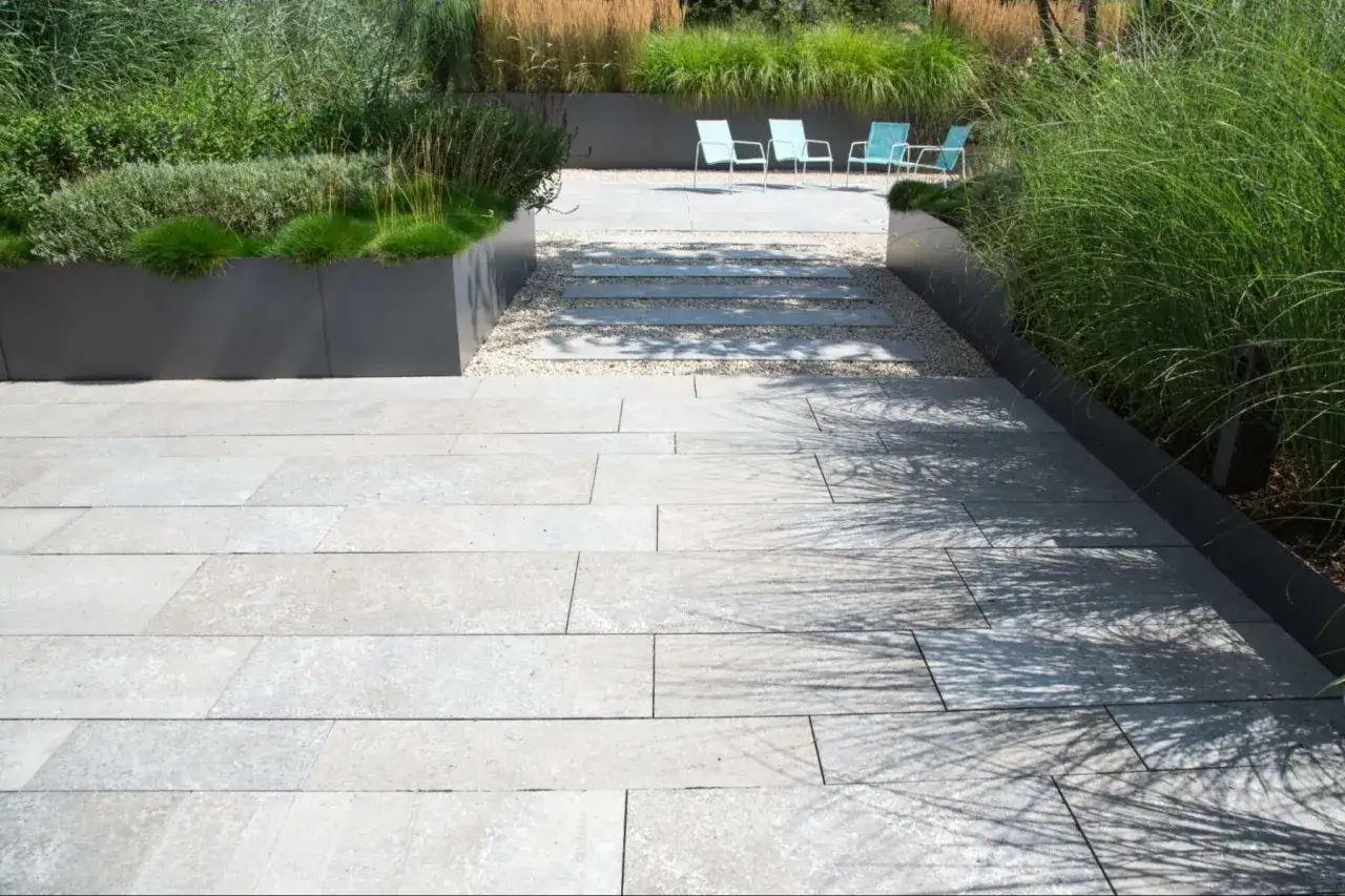 Terrasse moderne avec dalles de pierre claire. Les inconv&eacute;nients de la pierre reconstitu&eacute;e, comme la porosit&eacute;, peuvent &ecirc;tre visibles sur ce type de rev&ecirc;tement.