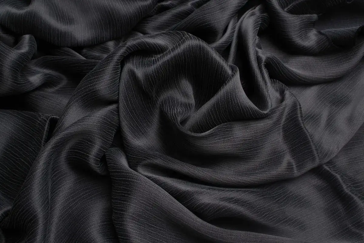 Ondas de cupro tejido negro, con un sutil patrón de líneas verticales que le dan profundidad y elegancia.