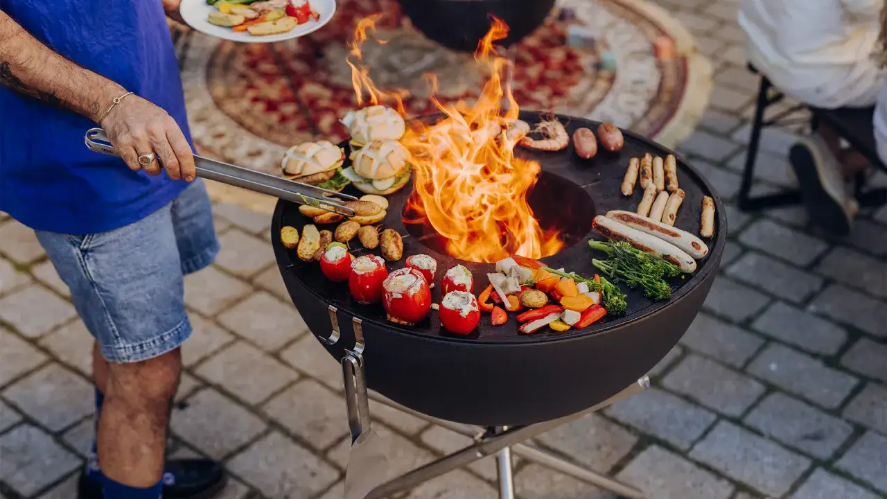 Une belle soirée barbecue avec des saucisses, des légumes grillés et des tomates farcies sur le feu.