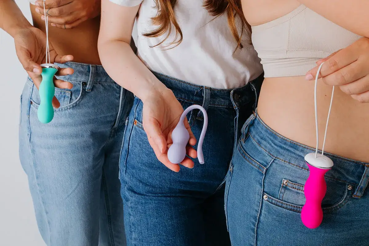 Trois femmes en jeans tiennent des objets colorés. Un avis de sage-femme sur le périnée.