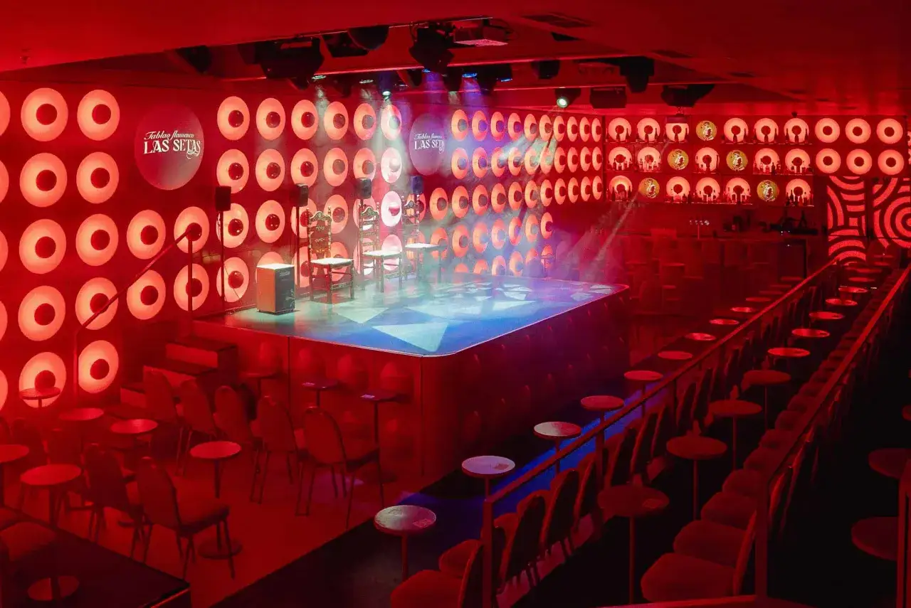 Escenario listo para un espectáculo de flamenco en el Tablao Las Setas, con sillas, cajón y luces rojas.