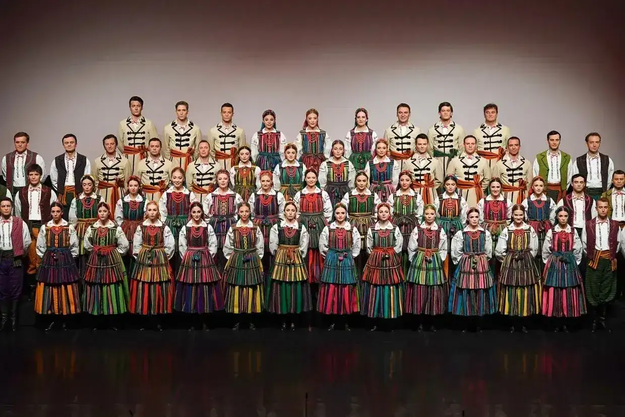 Zespół w strojach ludowych, gotowy do wykonania pieśni ludowych polskich.