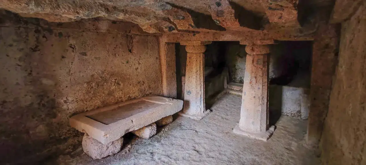 Antica tomba etrusca nel parco regionale Marturanum, con sarcofago in pietra e colonne scavate nella roccia.