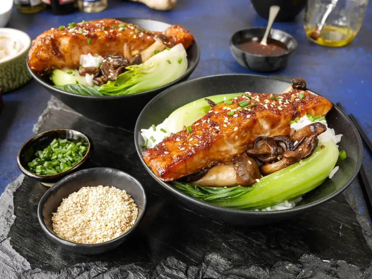 Två skålar med **sous vide lax**, ris, bok choy och svamp. Toppad med sesamfrön och gräslök.