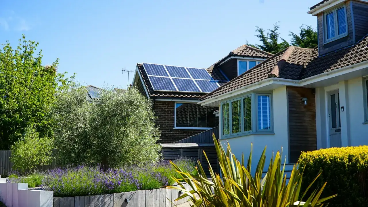 Panneaux solaires photovoltaïques sur le toit d'une maison, entourée d'un jardin verdoyant avec de la lavande.
