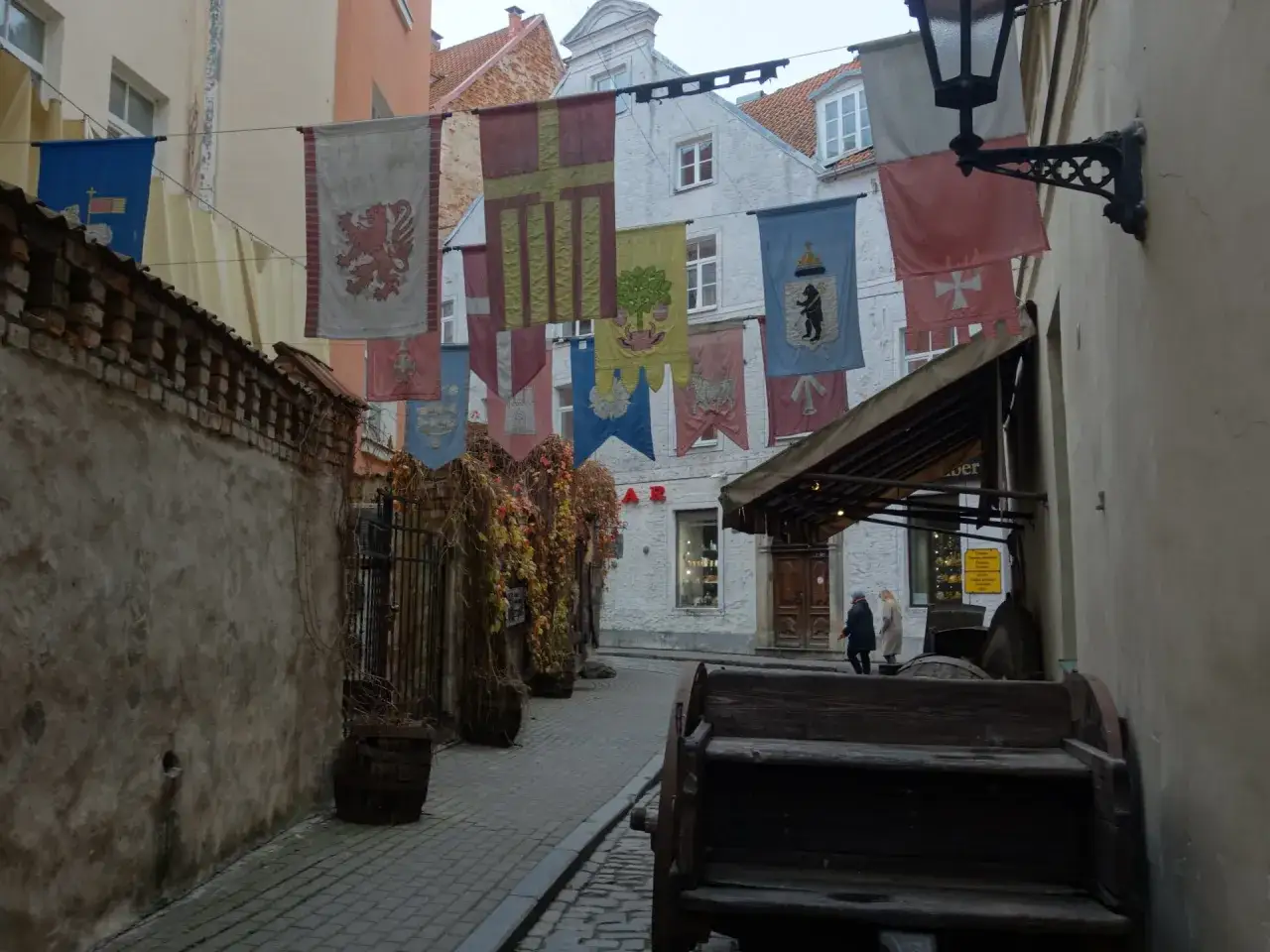 Ulica w Rydze z historycznymi banerami, beczkami i wozem. Idealne miejsce, by poczuć atmosferę i zobaczyć, co zobaczyć w Rydze.
