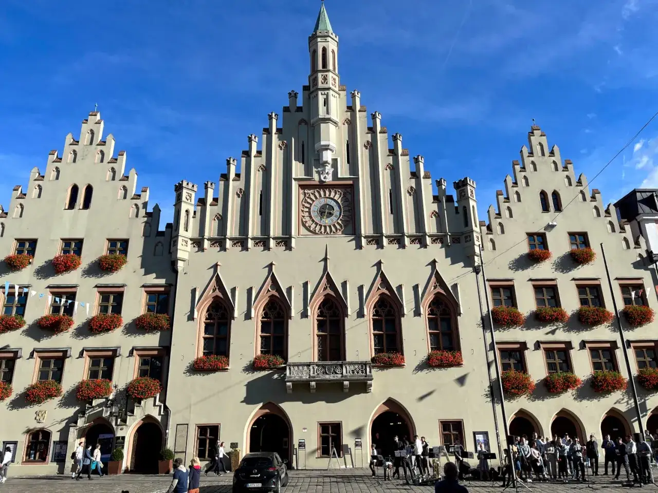 Prachtvolles Rathaus in der **Landshut Altstadt** mit blumengeschmückten Fenstern und einem Glockenspiel.