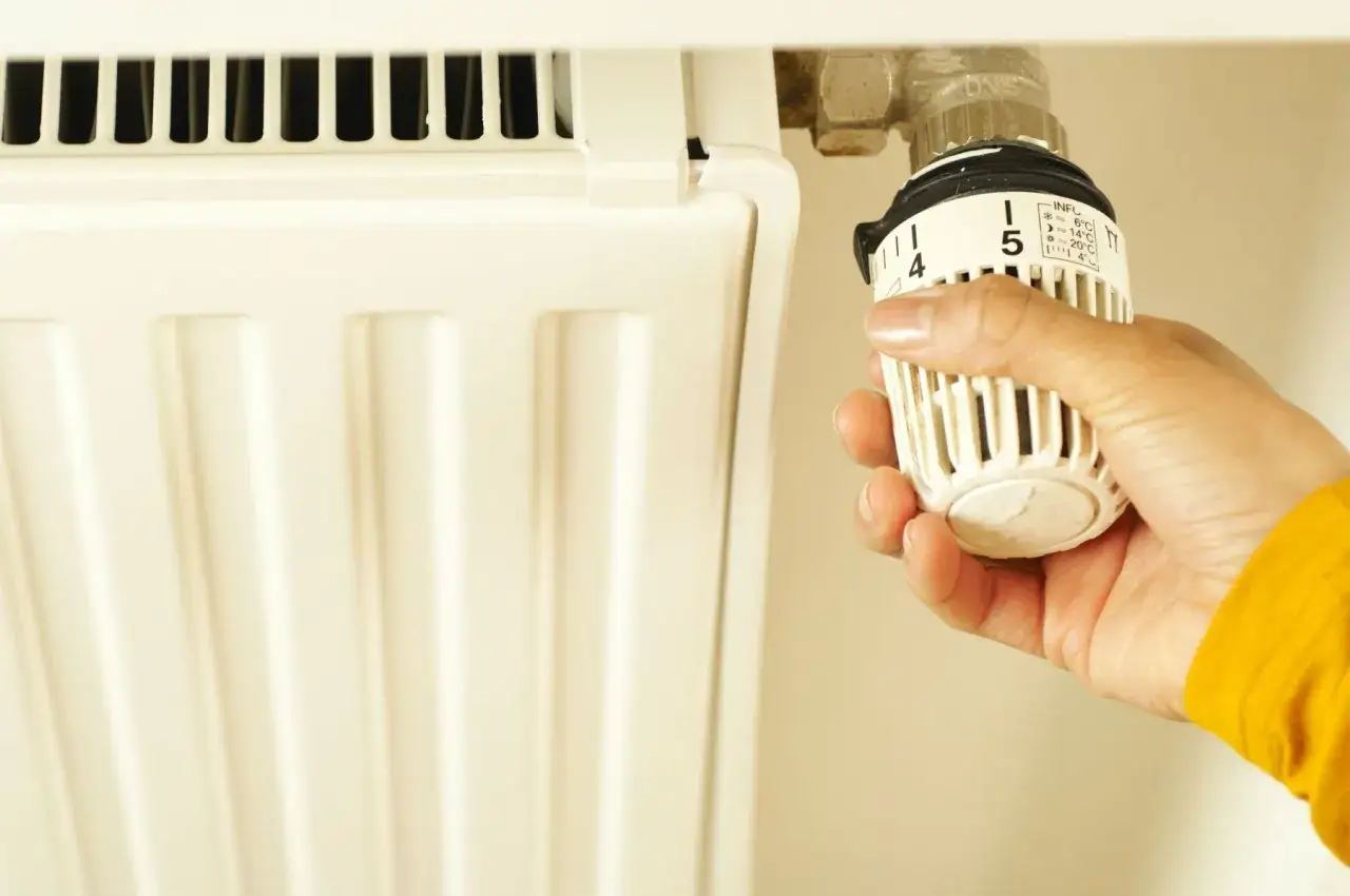 Mano che regola la valvola di un termosifone. Un gesto utile per capire quando spurgare i termosifoni e ottimizzare il riscaldamento.