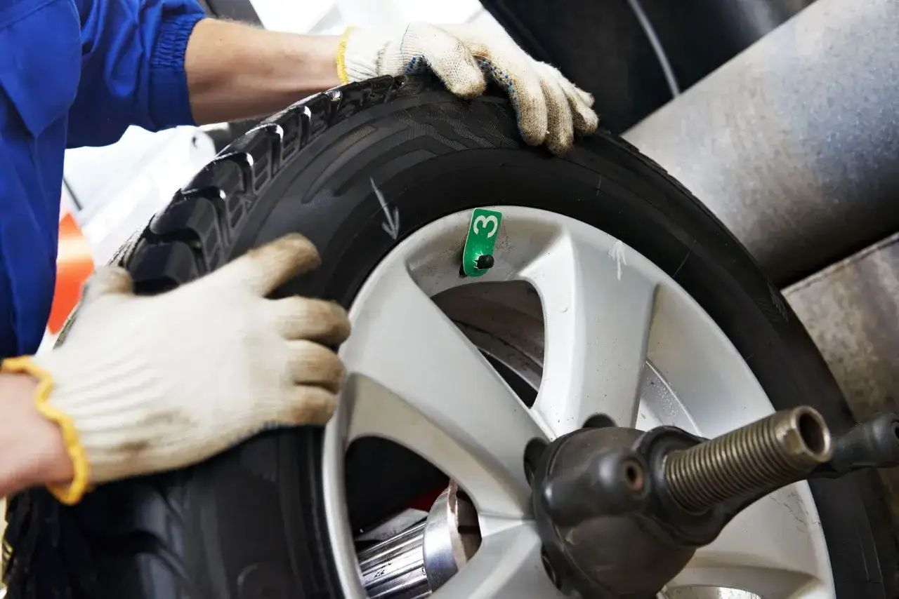 Meccanico con guanti esegue equilibratura gomme per eliminare vibrazioni.