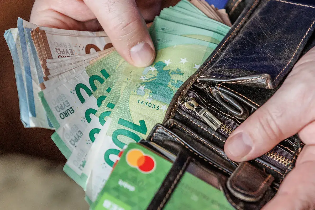 Ręka wyciąga z portfela banknoty euro. Odpowiedź na pytanie: jaka waluta na Litwie? to euro.