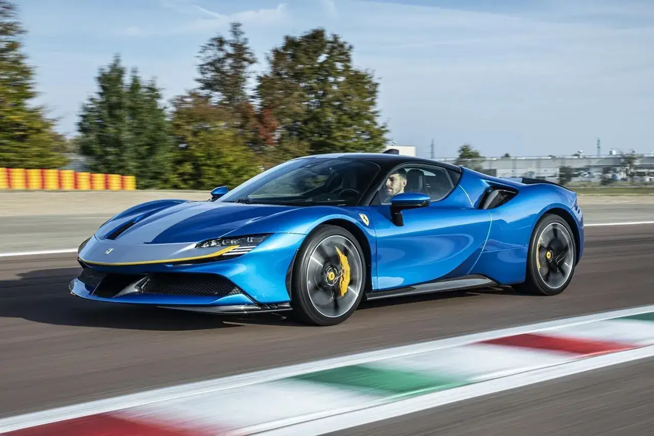 Niebieskie Ferrari SF90 z żółtymi akcentami pędzi po torze wyścigowym, kierowca wpatrzony w drogę.