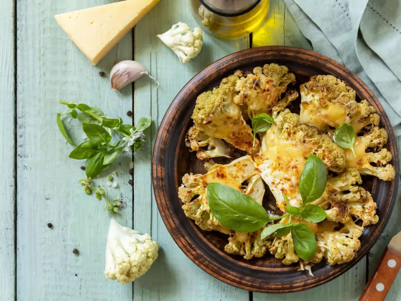 &Uuml;berbackener Blumenkohl mit K&auml;se und Basilikum, bereit zum Servieren. Perfekt, wenn Sie Blumenkohl kochen m&ouml;chten.