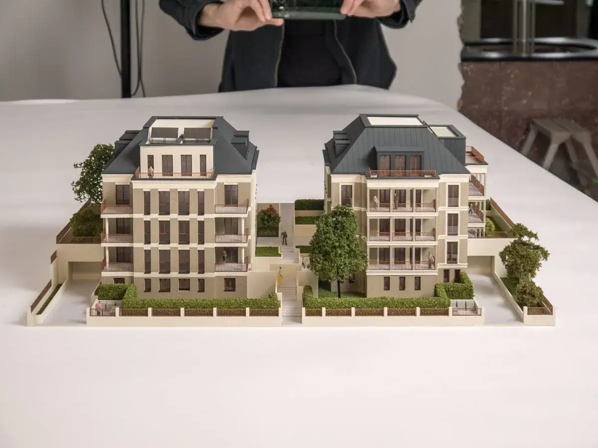 Architekturmodell eines modernen Wohnkomplexes, inspiriert vom **Dortmund Architektur Studium**. Zwei Geb&auml;ude mit Balkonen und begr&uuml;nten Au&szlig;enbereichen.