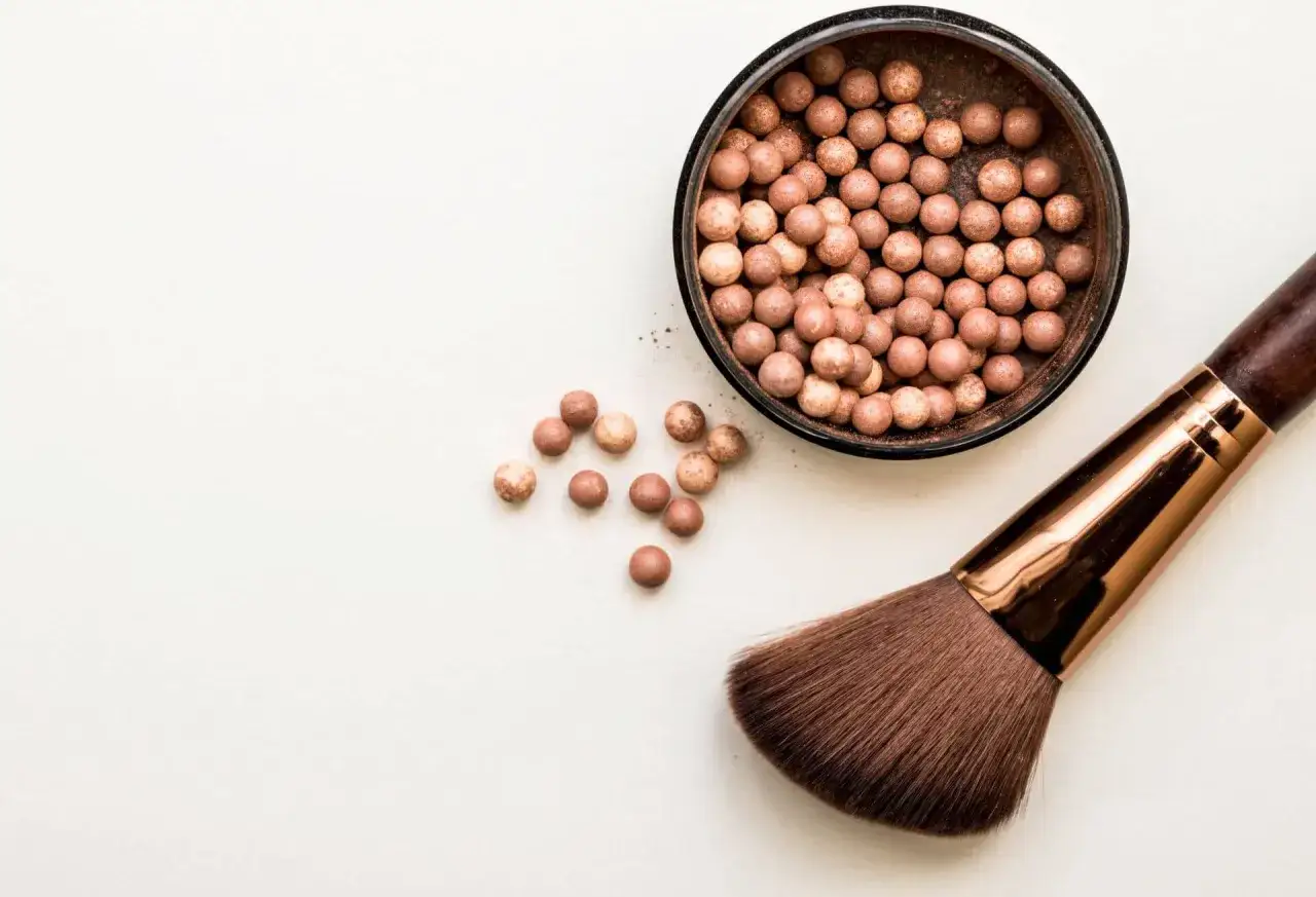 Puder w kulkach i pędzel do makijażu. Idealny wybór, jeśli zastanawiasz się, jaki puder do twarzy wybrać, by uzyskać naturalny efekt.