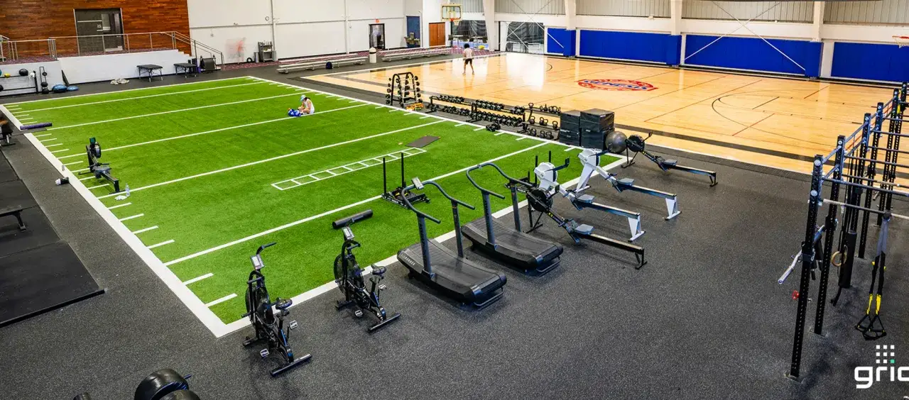 Instalación deportiva con campo de césped artificial, pista de baloncesto y zona de entrenamiento con máquinas de remo, cintas de correr y bicicletas estáticas. Los pavimentos deportivos son ideales para este tipo de espacios.