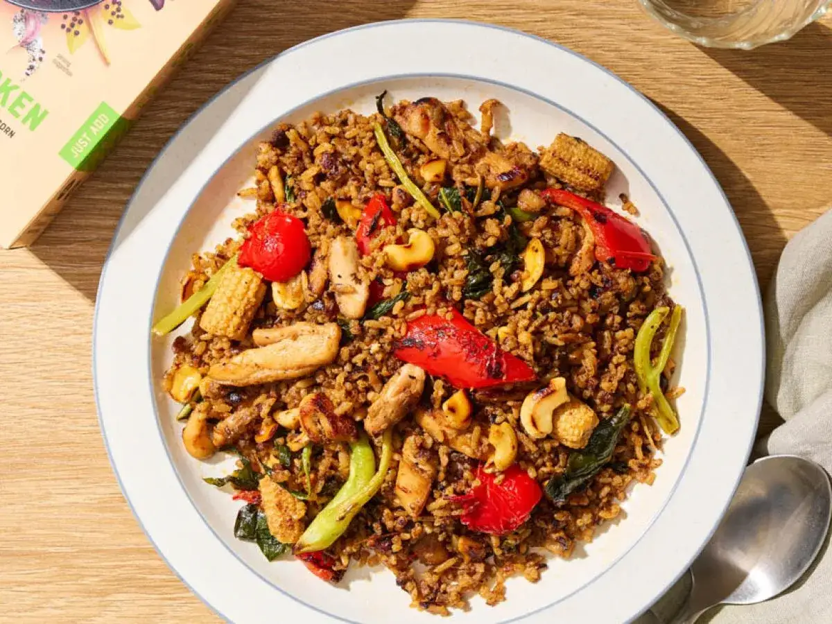 En tallrik med kyckling cashew-ris, full av färgglada grönsaker och nötter. En läcker måltid som ser ut att vara redo att avnjutas.