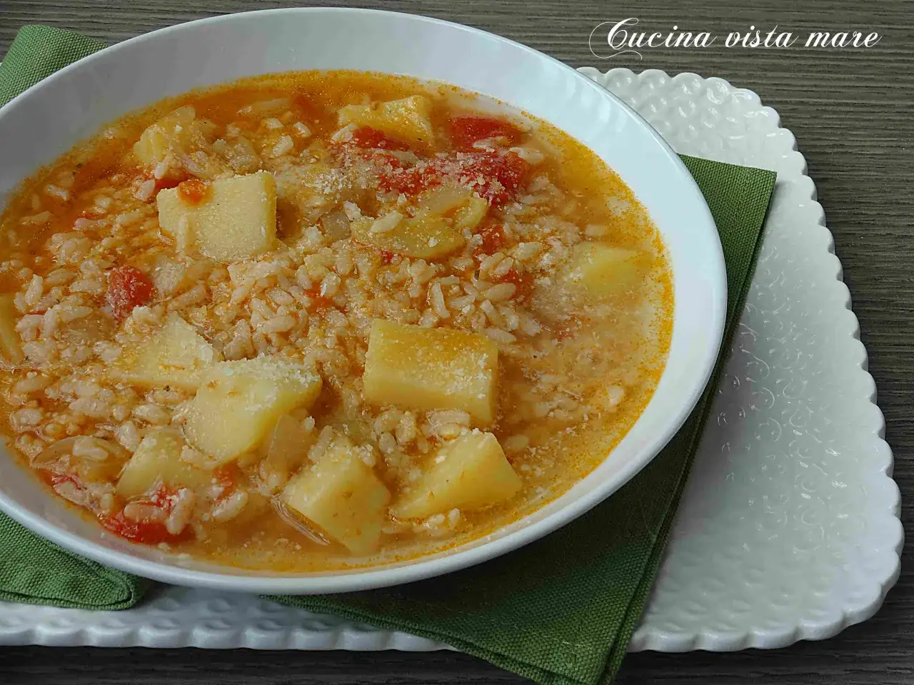 Una ciotola di zuppa calda con riso e patate a cubetti, condita con parmigiano grattugiato. Un piatto confortante e saporito.