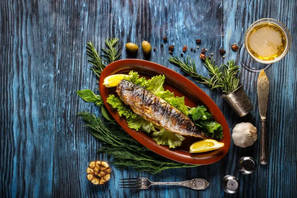 Apetyczna, wędzona makrela na talerzu z ziołami i cytryną. Czy makrela wędzona jest zdrowa? Tak, to bogactwo kwasów omega-3!
