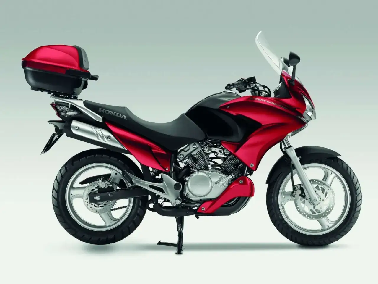 Czerwony motocykl Honda Varadero 125 z kufrem, gotowy do odblokowania pełnej mocy.