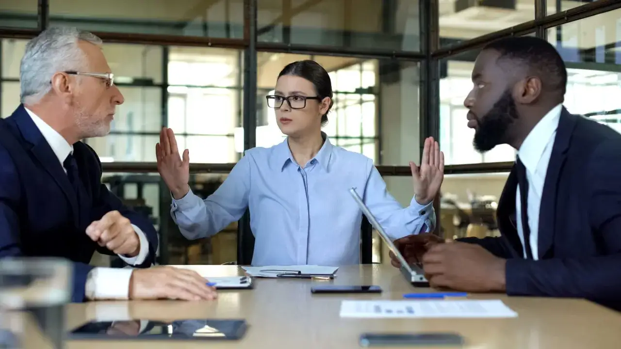 A woman holds up her hands, setting boundaries to protect herself in a toxic work environment.