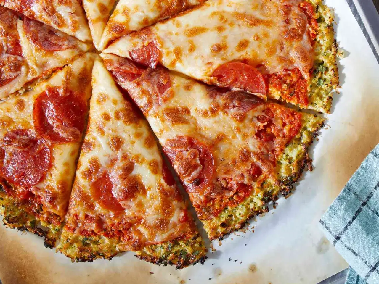 Eine köstliche blumenkohl pizza vegan mit geschmolzenem Käse und Pepperoni-Scheiben, auf einem Backblech serviert.