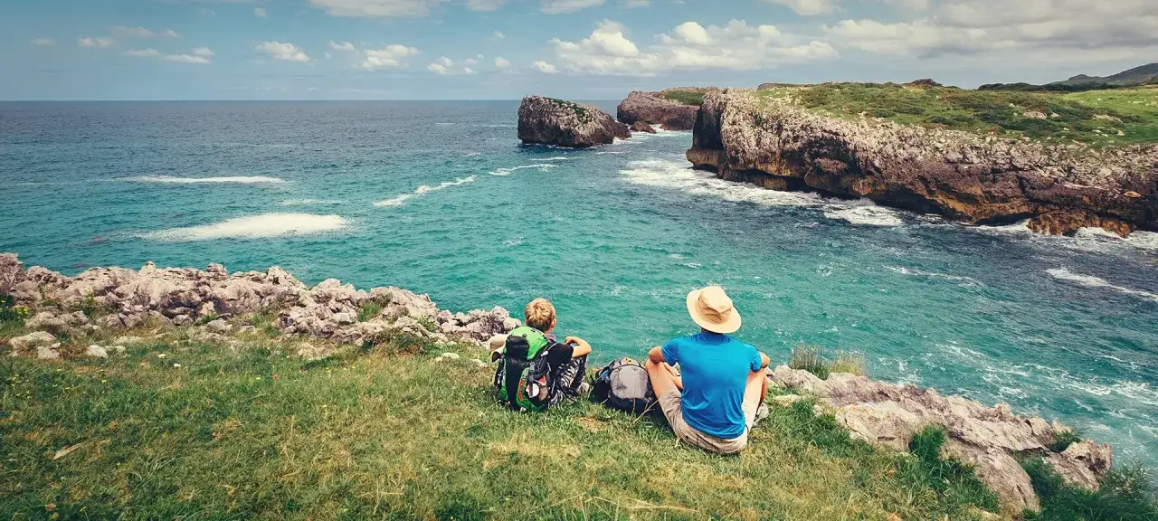 Dos peregrinos disfrutan de la vista del mar Cantábrico en el **camino de Santiago norte**.