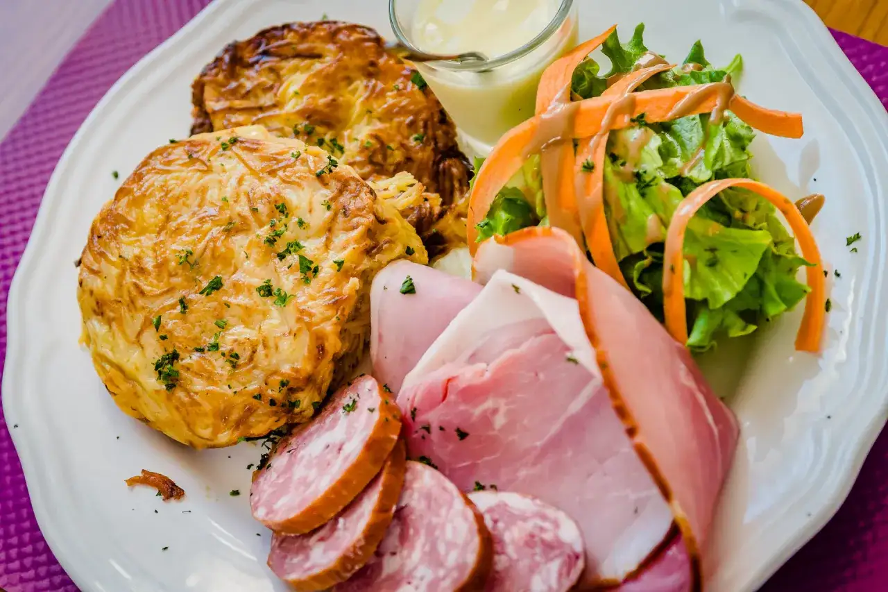 Assiette gourmande : galettes de pommes de terre, jambon, saucisson, salade et sauce. Une spécialité Franche-Comté à savourer.