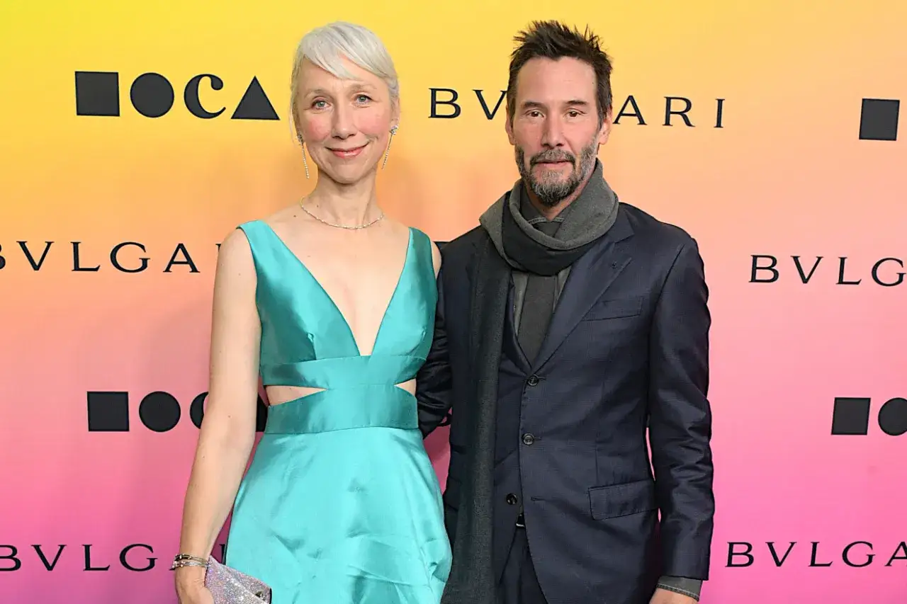 Alexandra Grant wzrost jest widoczny obok Keanu Reevesa. Oboje pozują na tle z logo Bvlgari.