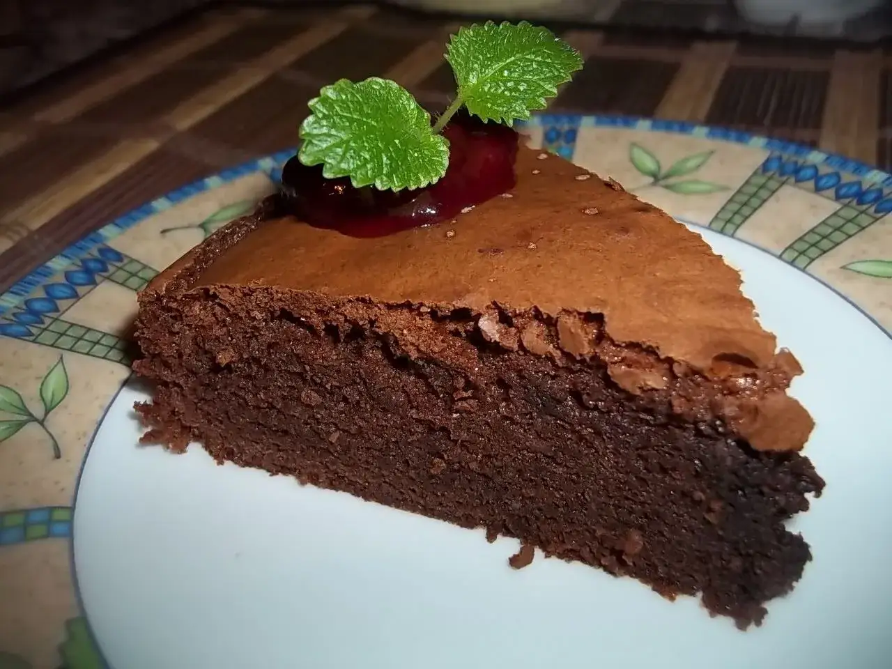 Wilgotny brownie przepis na pyszny deser. Kawałek ciasta udekorowany wiśnią i miętą.